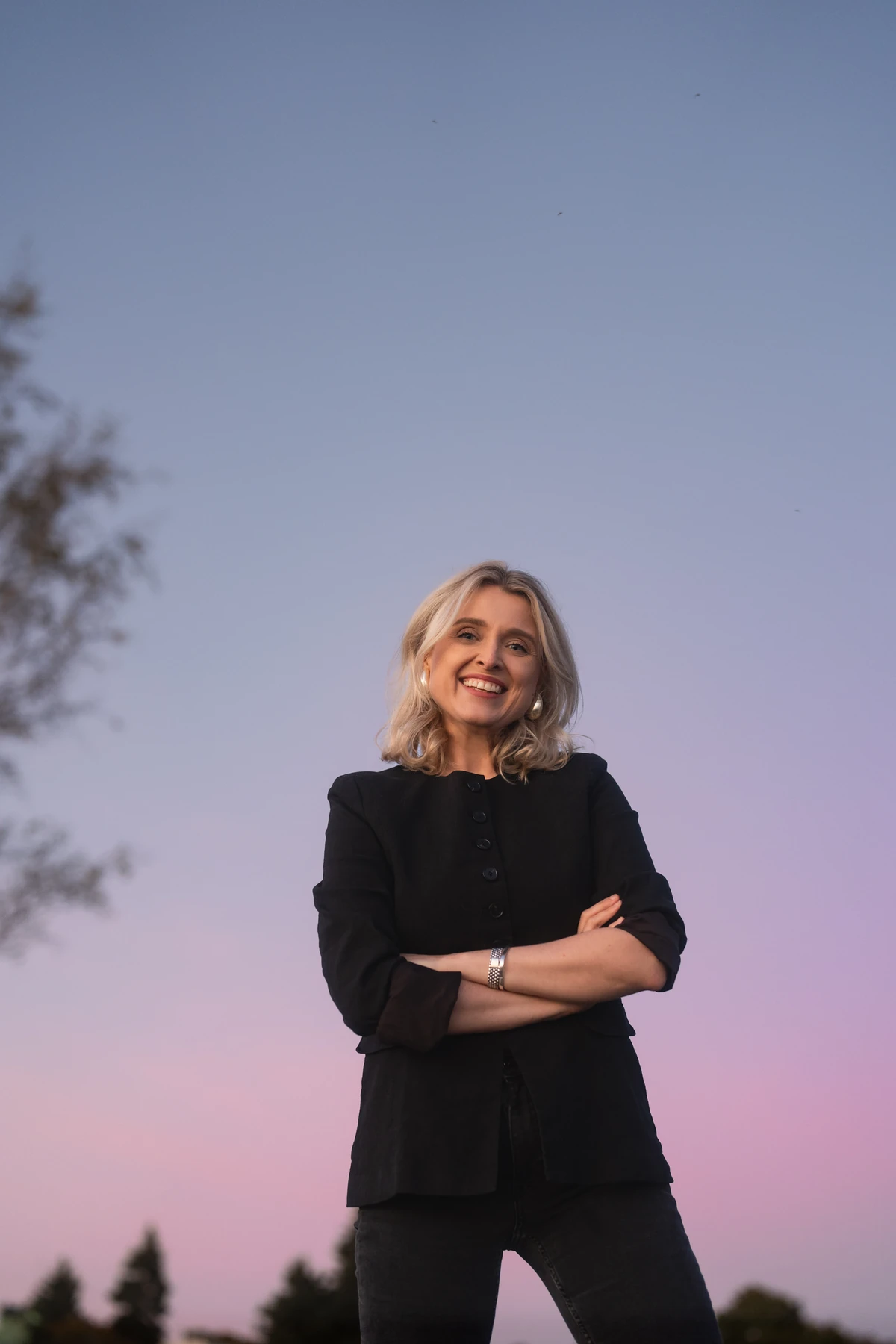 Joanna Numminen, founder of Numminen Advisory, smiling with arms crossed against a dusk sky in Helsinki