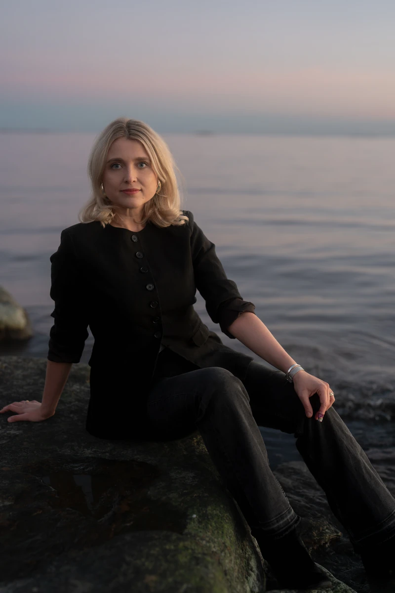Joanna Numminen, founder of Numminen Advisory, on a seaside rock at dusk in Helsinki